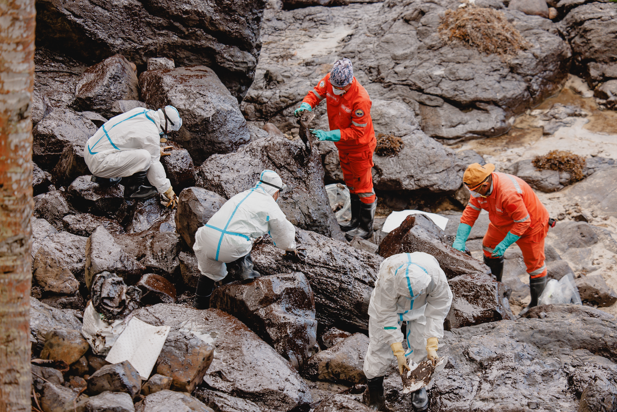 People in protection suits cleaning up an oil spill at the beach