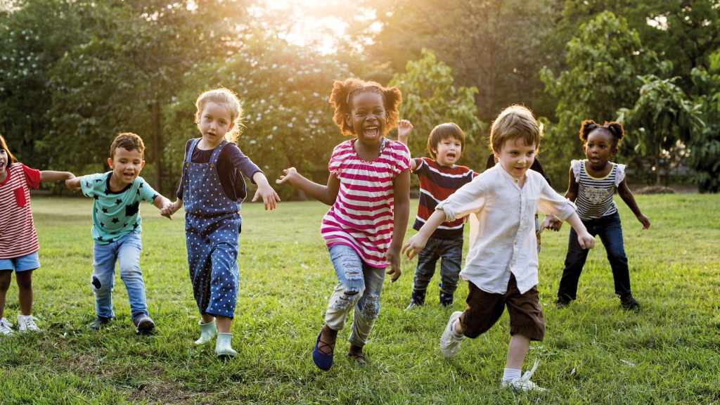 Kinder laufen lachend über eine Wiese